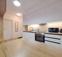 A kitchen in a 2-room apartment with a wooden countertop and white cabinets.