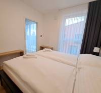 A bedroom in a two-room apartment with two beds, wooden tables, and curtains.
