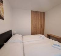 A bedroom in a two-room apartment with a bed, a wooden wardrobe, and a picture on the wall.