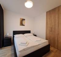 Bedroom with a double bed, tables, and a wardrobe in a 2-room apartment.