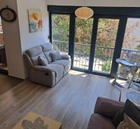 Living room of a three-room apartment with a sofa, balcony, and a high chair for toddlers.