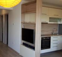 A kitchen in a 3-room apartment with built-in appliances and a TV on the wall.