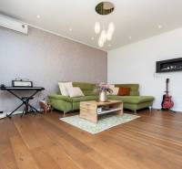 Living room in a family house with a piano, a sofa, and two guitars on a wooden floor.