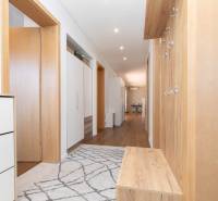Entrance hallway with wooden doors, cabinets, and coat hooks in a family house.