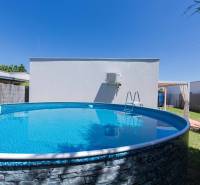 A swimming pool in the garden of a family house in Senec, surrounded by greenery and a fence.
