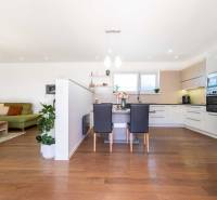 Living room and kitchen in a family house with wooden flooring and a green sofa.