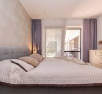 Bedroom in a family house with a bed, wallpaper, and a dresser with decorations.