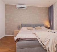 A bedroom in a family house with a comfortable bed, elegant curtains, and a patterned wall.