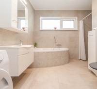 A bathroom in a family house with a bathtub, washing machine, and window.