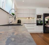 A kitchen in a family house with wooden flooring, modern appliances, and a large refrigerator.