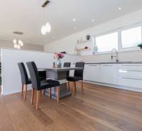 Kitchen in a family house with a dining table, chairs, and light-colored furniture.