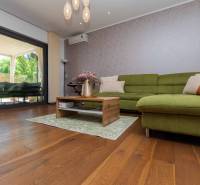 Living room in a family house with wooden flooring and a green sofa.