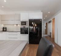 A kitchen in a family house with white cabinets, a black refrigerator, and wooden flooring.