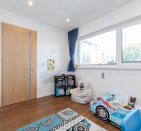 Children's room in a family house with toys, a car-shaped bed, and wooden flooring.