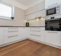 A kitchen in a family house with built-in appliances and a wooden floor.