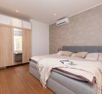 A bedroom in a family house with a wooden floor, a bed, and a built-in wardrobe.