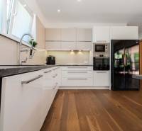 A kitchen in a family house with white cabinets, wooden flooring, and stainless steel appliances.