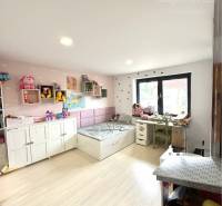 Children's room with toys in a family house, light flooring and storage cabinets.