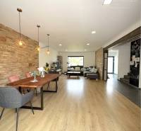 Interior of a family house with a dining table, brick wall, and wooden floor.