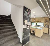 Interior of a family house with a black staircase, kitchen, and chalkboard wall.