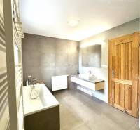 Bathroom in a family house with a bathtub and wooden door.