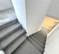 Interior of a family house with a staircase covered in carpet and a wooden floor below.