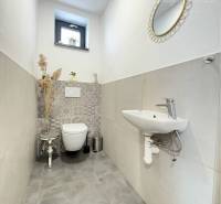 A toilet in a family house with a window, a mirror, and a decorative stool.