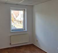 A room with a window, a radiator, and white walls in a building.
