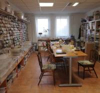 The interior of a building with tables and shelves full of materials for creative activities.
