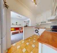 A kitchen in a 2-room apartment with a bar counter and a living room in the background.