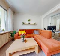 Living room in a two-room apartment with an orange sofa, coffee table, and large window.