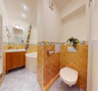 Bathroom with a corner bathtub, white sink, and toilet with warm tiles.