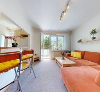 A bright living room in a two-room apartment with an orange sofa and access to the balcony.