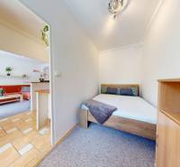 Bedroom with a double bed and entrance to the living room in a 2-room apartment.