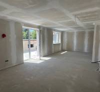 Interior of a family house with unplastered walls and large windows.