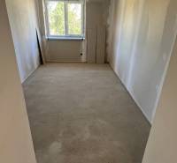 An empty room with a window, white walls without flooring in a family house.