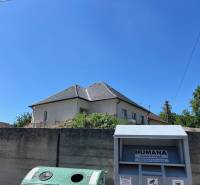 A family house in Sasinkovo on Sasinkovo Street behind a concrete fence with a blue sky.