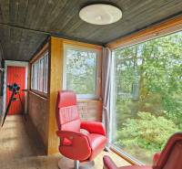 A family house with a glass veranda, red armchairs, a telescope, and a view of the forest.