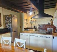A kitchen in a family house with a wooden ceiling, a stove, and a solid table.