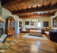 Living room in a family house with a fireplace, wooden ceiling, and comfortable sofas.