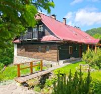 A family house in Donovaly with a wooden facade and a red roof in a natural environment.