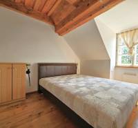 Attic bedroom in a family house with roof beams and a large window.