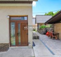 A family house in Dolná Mariková with a terrace, stone wall, and garden furniture.