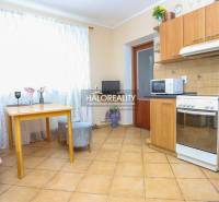 The kitchen in the family house contains a table, chairs, a kitchen unit, and appliances.