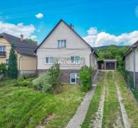 A family house in Dolná Mariková, with an access road and surrounding greenery under a blue sky.