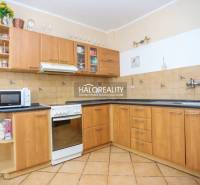 A kitchen in a family house with wooden cabinets and light tiles.