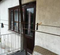 A balcony of a family house in Bzovík with wooden doors and railing.