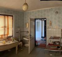 Interior of a family house with furniture, windows with blinds, and wallpapered walls.