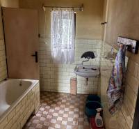 A bathroom in a family house with a bathtub, a sink, and tiles on the wall.