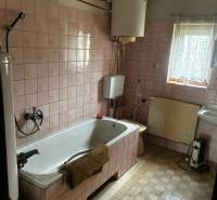 A bathroom in a family house with pink tiles and a classic bathtub.